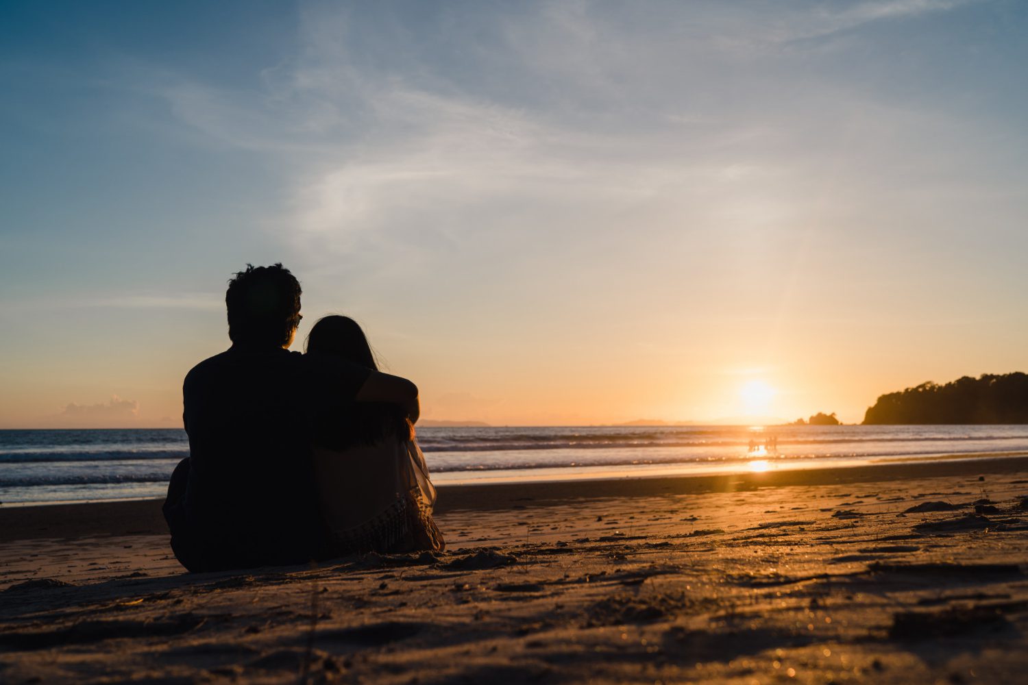 A young couple watching the sunset at the beach