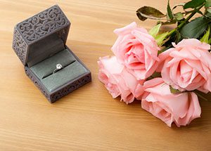 An engagement ring in a box and flowers