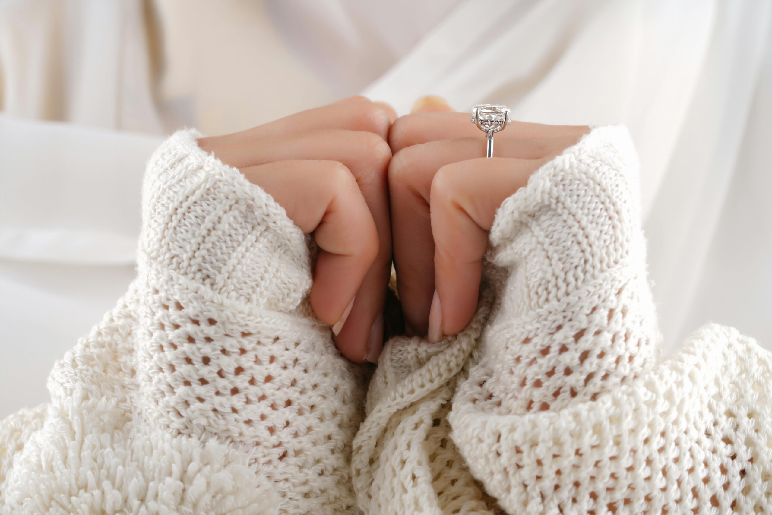A woman in a white sweater wearing a diamond wedding ring